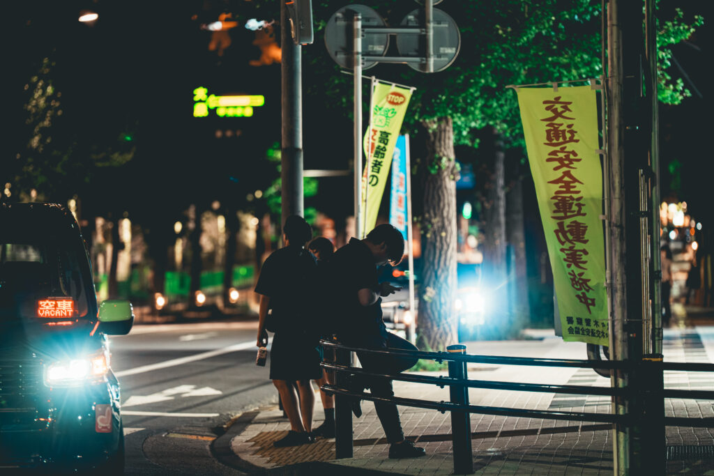 交差点のガードレールでスマホをいじる男性