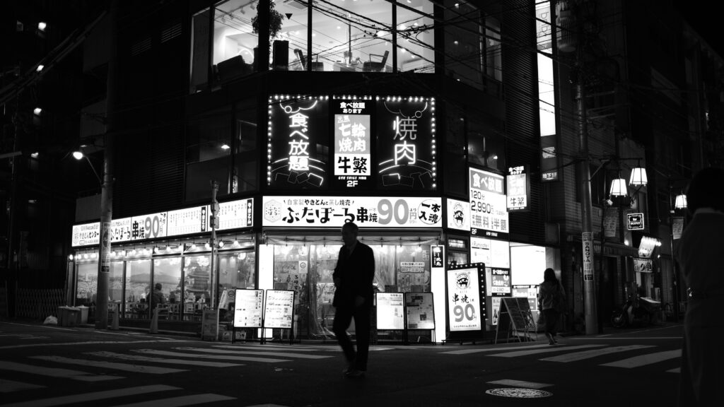 焼肉屋の前を歩く男性のシルエット