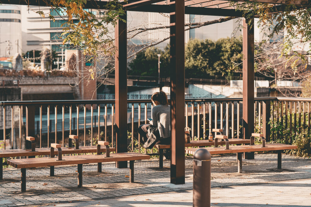 目黒川沿いの遊歩道でベンチに座る女性