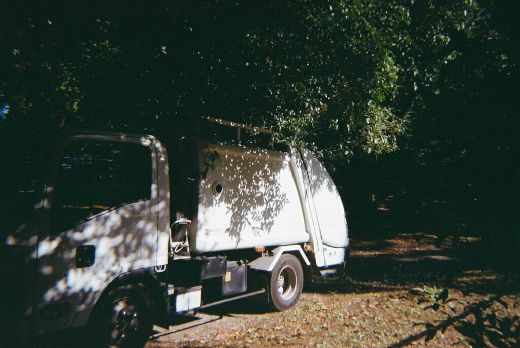 白いゴミ収集車に映る木漏れ日